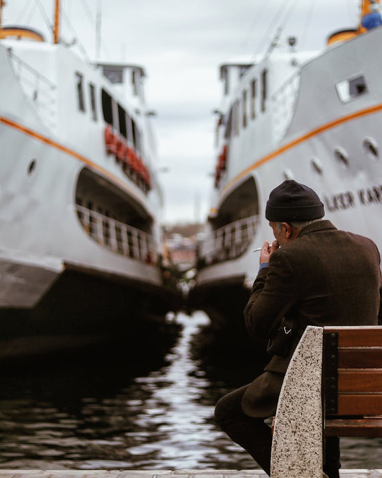 Man Sitting On Bench And Looking At Ships