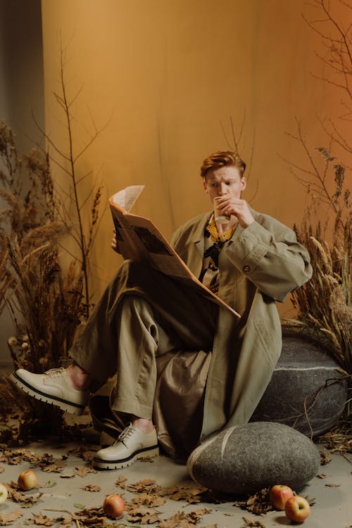 Redhead Model in Coat Reading Newsaper and Drinking Coffee