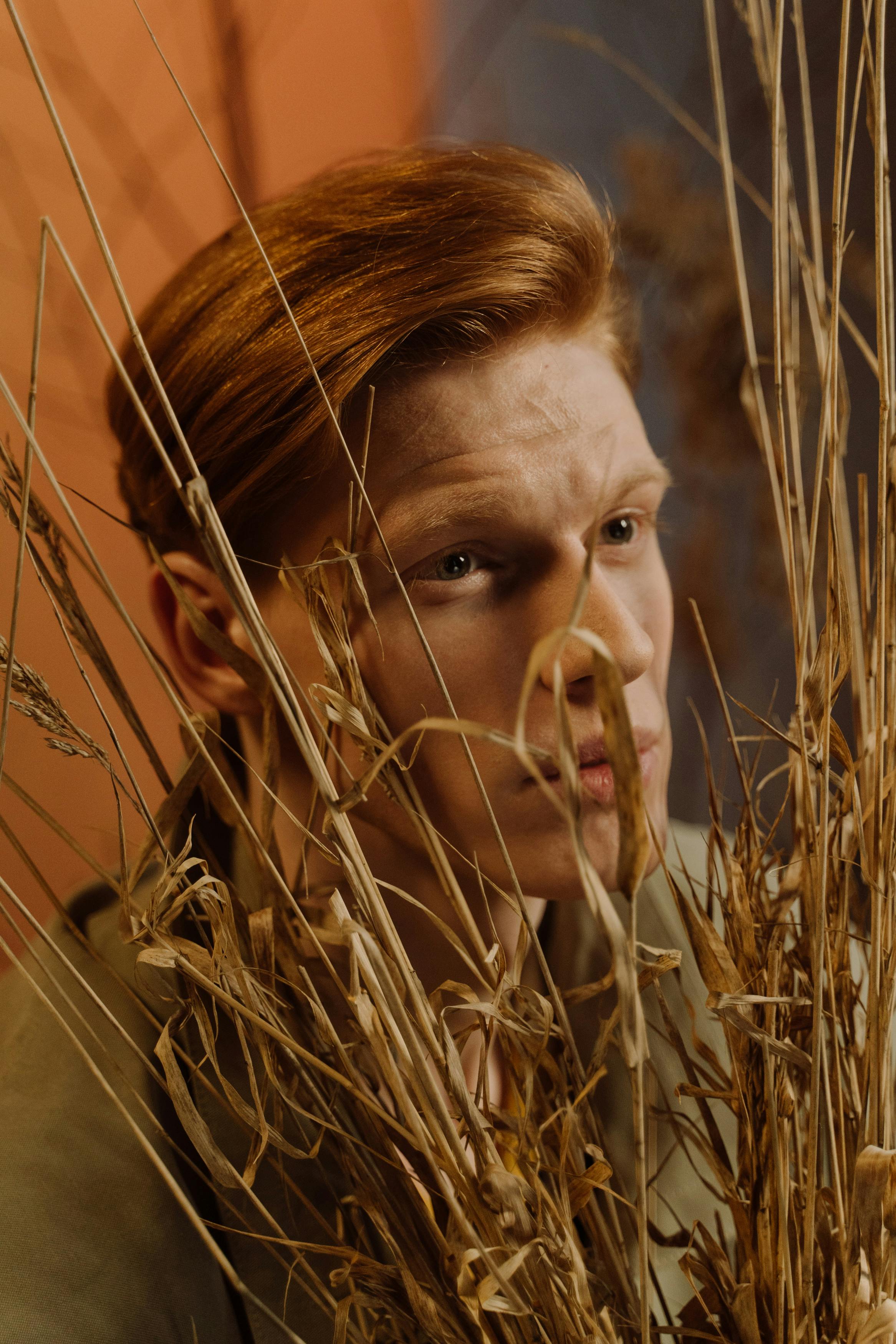 man posing under a bunch of dry wheat