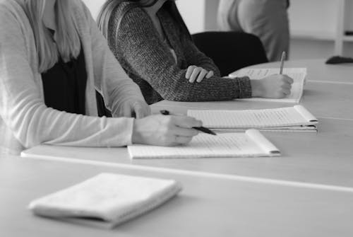 A Person in Black Long Sleeve Shirt Writing on White Paper