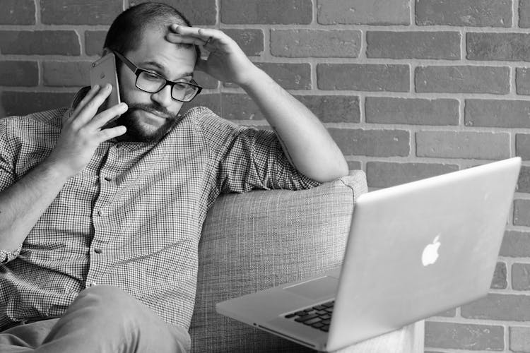 A Worried Man Talking Into A Smartphone 