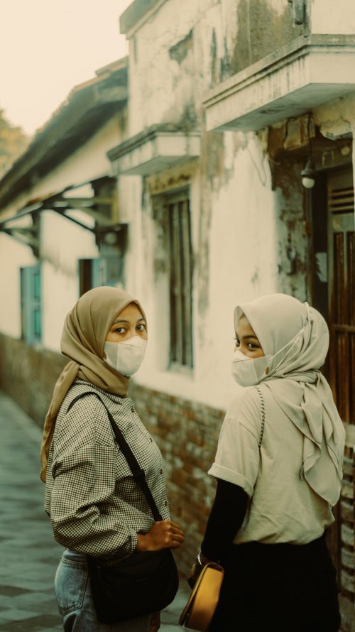Free Two women wearing hijabs and face masks standing in an old street alley. Stock Photo