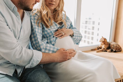 Man Sitting Beside a Pregnant Woman