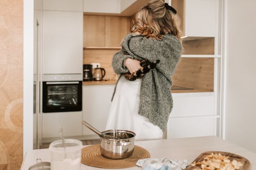Free Pregnant Woman Hugging her Cat While Cooking Stock Photo