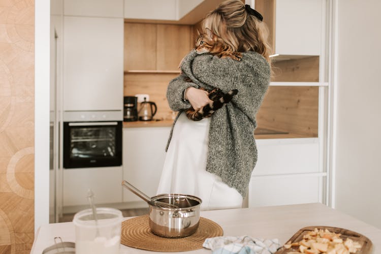 Pregnant Woman Hugging Her Cat While Cooking