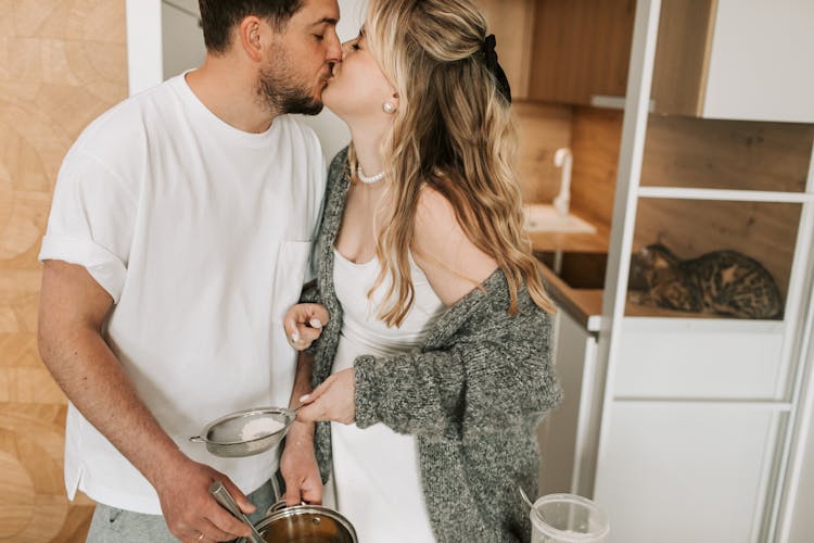 Couple Kissing While Cooking In The Kitchen