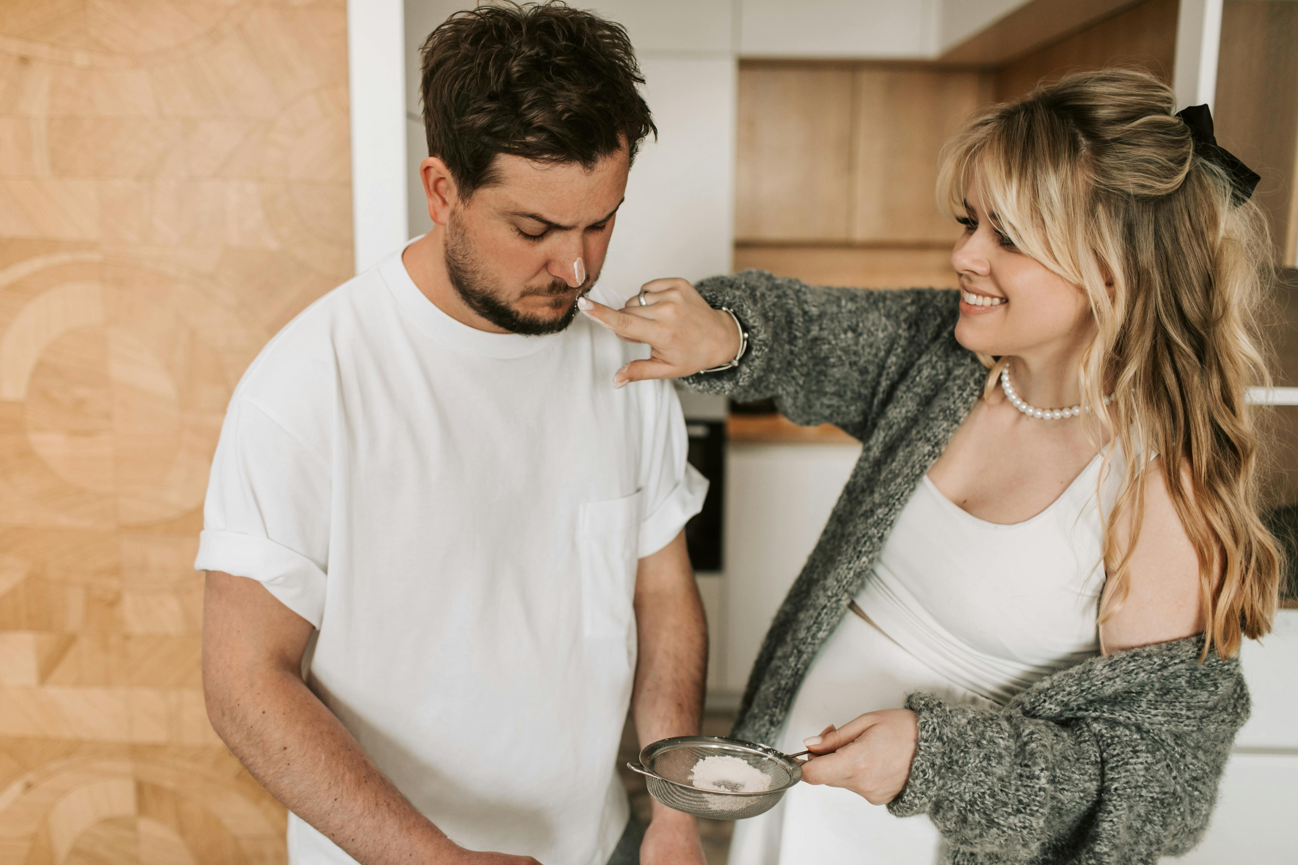 pregnant woman putting powder on man s nose