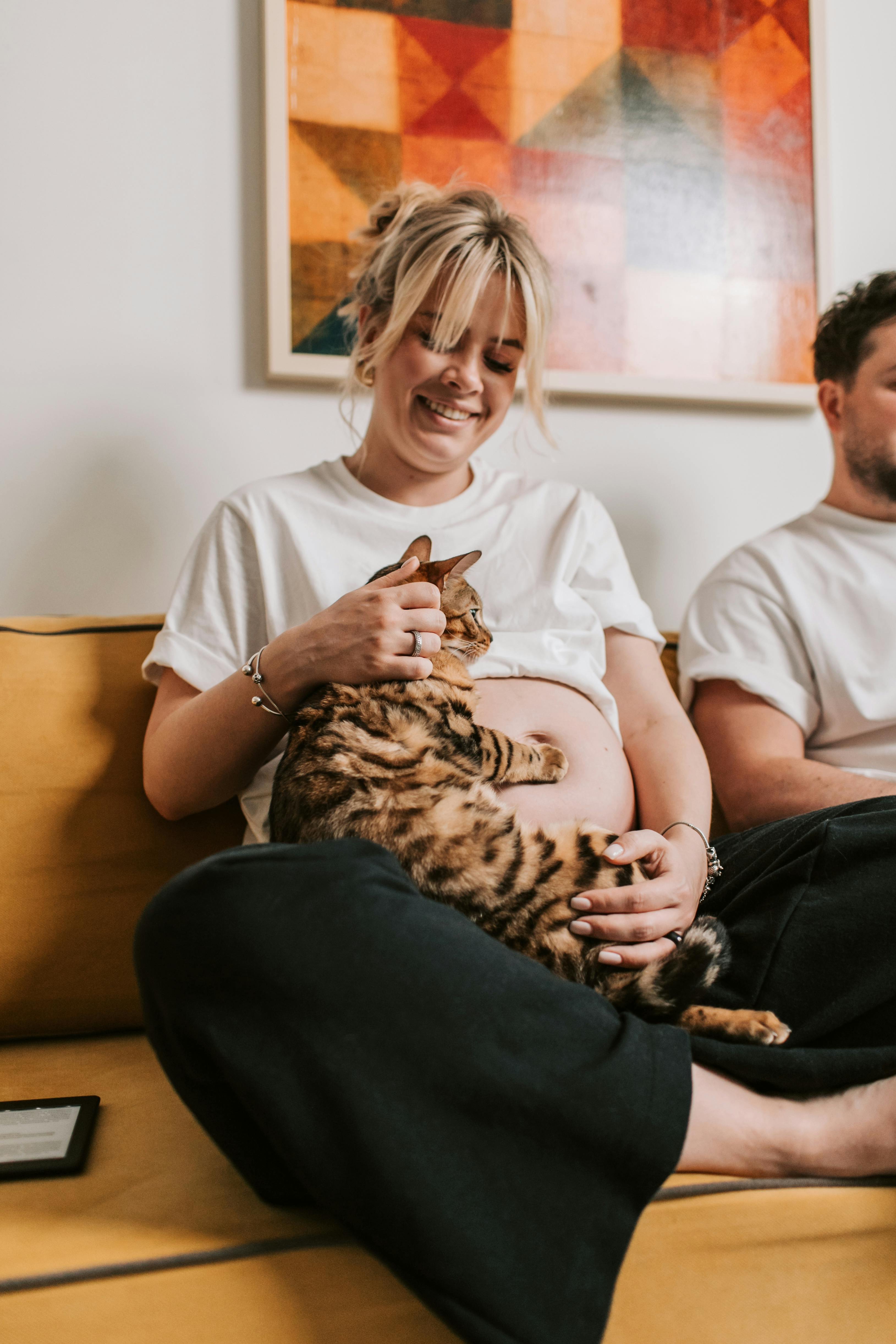 pregnant woman sitting on sofa while holding a cat