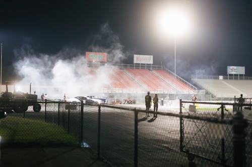 Racing Cars with Smoke on a Race Track During Night Time