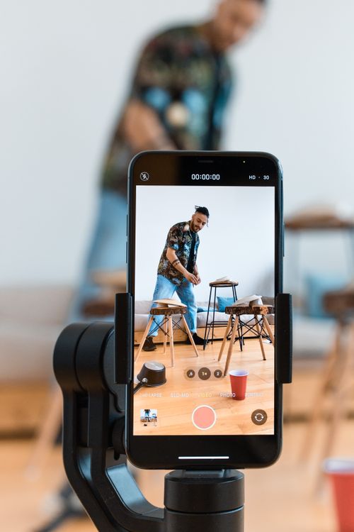 Free A person filming content using a smartphone and tripod setup indoors. Stock Photo