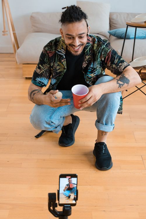 Free African American man smiling while recording content in a living room. Stock Photo