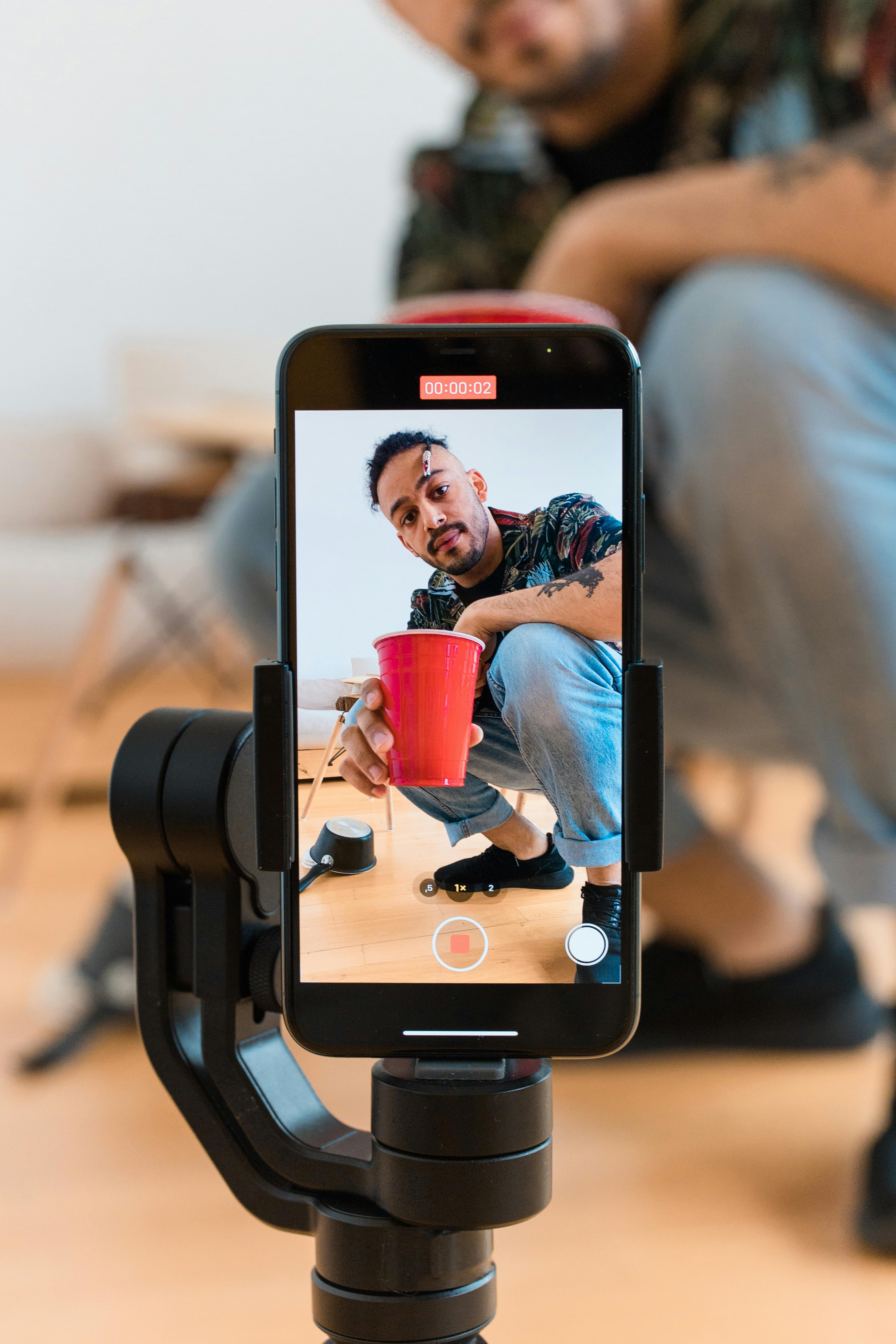 a man holding a red cup while recording himself