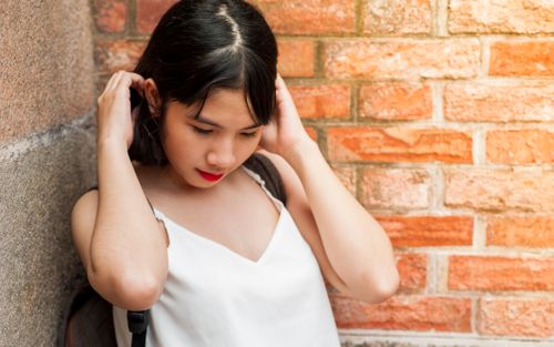 Free Stylish young woman in white top poses thoughtfully against a rustic brick wall. Stock Photo