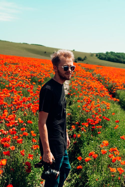 A Man in a Black Shirt Standing on a Flower Field 