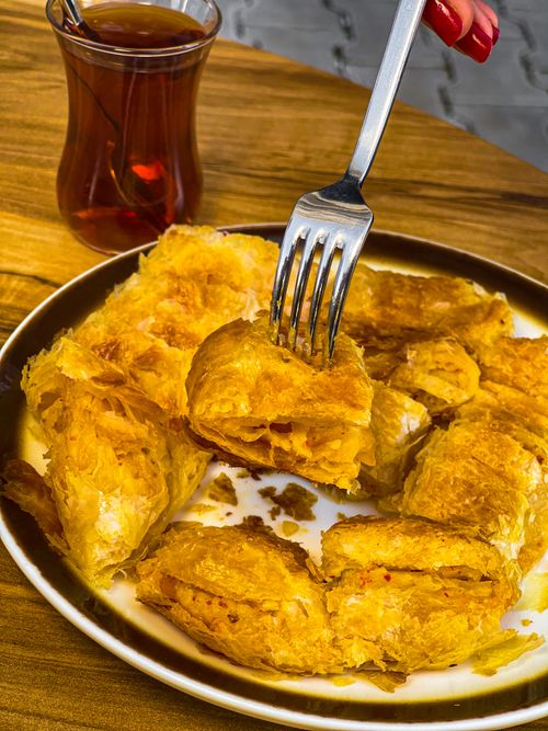 Free Close-up of flaky Turkish pastry on a plate with a glass of tea, perfect for a vertical shot. Stock Photo