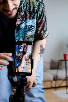Man filming content on a smartphone indoors, focusing on casual lifestyle and technology.
