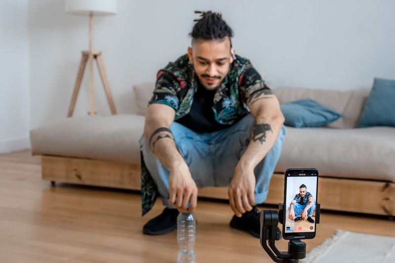 Hombre produciendo un video con un smartphone en casa
