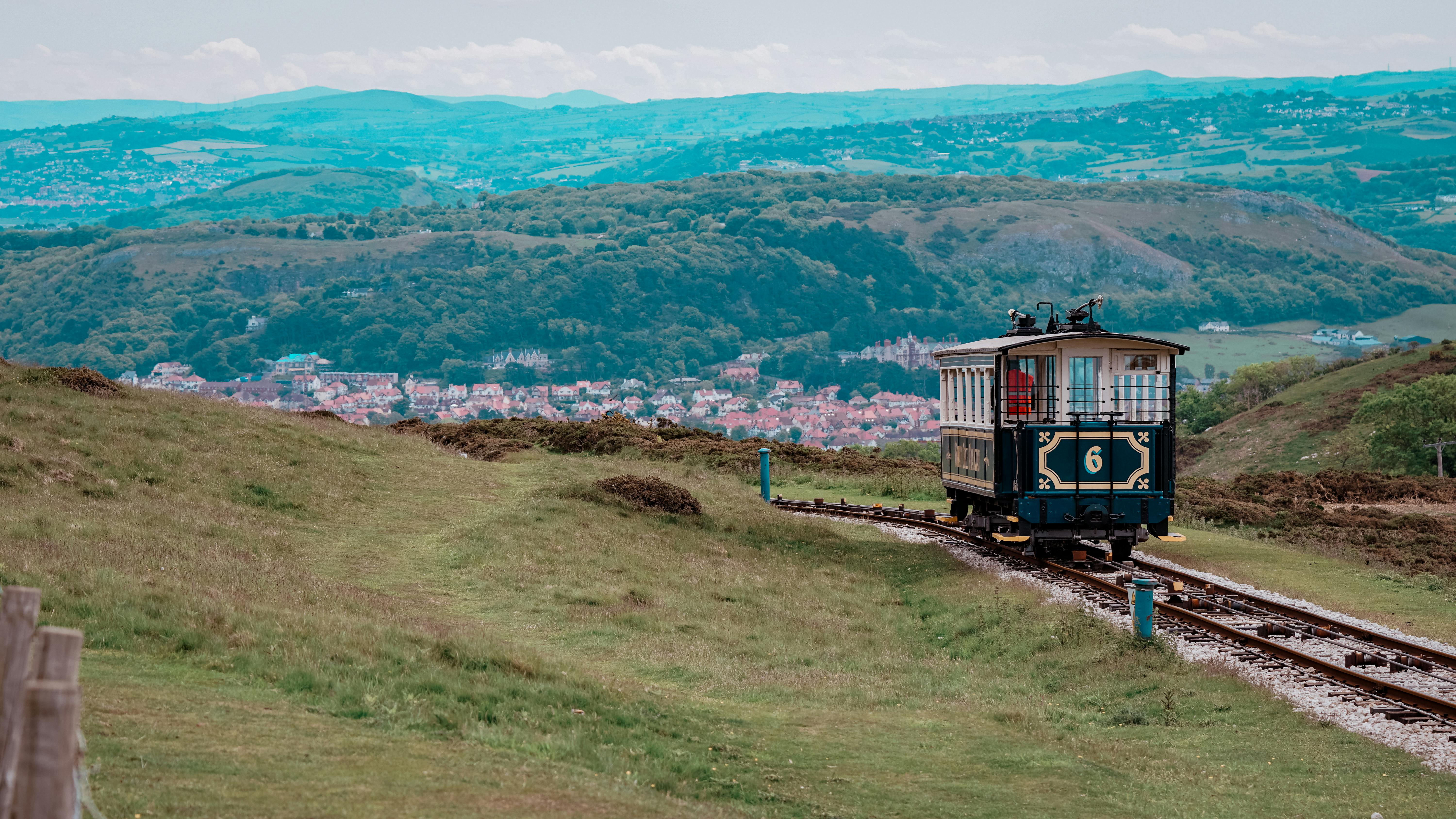 A scenic view of a vintage tramway traveling through Llandudno, Wales' lush hills.