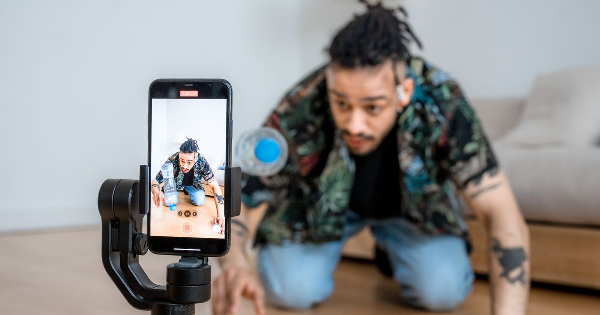 Une personne filme avec un téléphone monté sur stabilisateur à l’intérieur d’une pièce