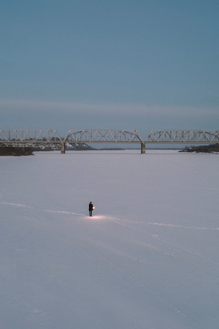 Person Standing On Snow Covered Ground Near The Bridge