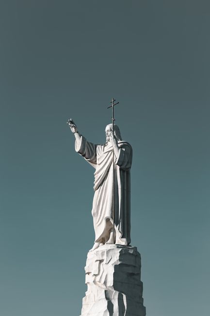 A monumental statue of Jesus with an outstretched arm against a clear blue sky in Kislovodsk, Russia.