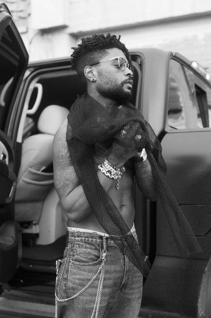 Portrait of a fashionable young man with a beard standing by a car door in Houston, TX.