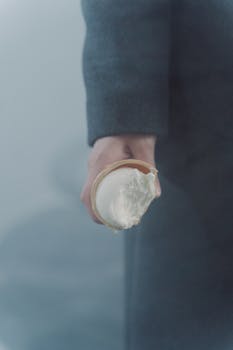 A person holding a partially eaten ice cream cone in a misty outdoor setting.
