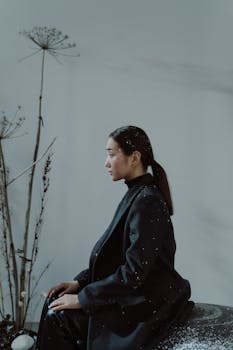 Elegant side profile of an Asian woman in a coat, surrounded by winter elements.
