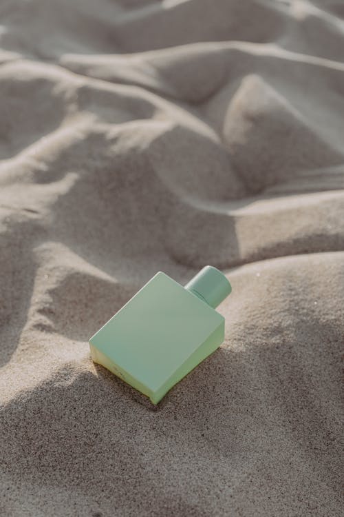 Green Square Perfume Bottle on Sand