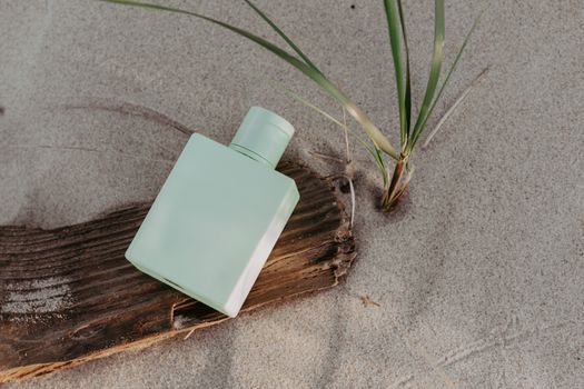 Ocean-themed perfume bottle displayed on sandy beach with wooden texture.