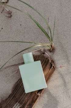 Elegant perfume bottle on sand with natural elements, perfect for product mockups.