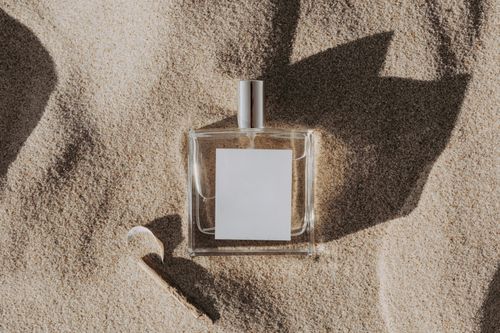 Free Elegant perfume bottle casting shadows on sand, ideal for beauty product concepts. Stock Photo