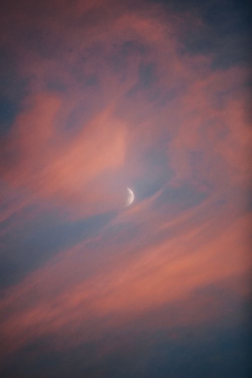 Free Captivating dusk sky with a crescent moon amidst vivid pink clouds. Stock Photo