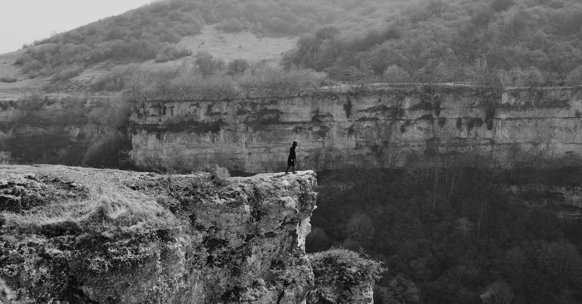 a person standing on a cliff edge overlooking a sunrise, symbolizing release and new beginnings