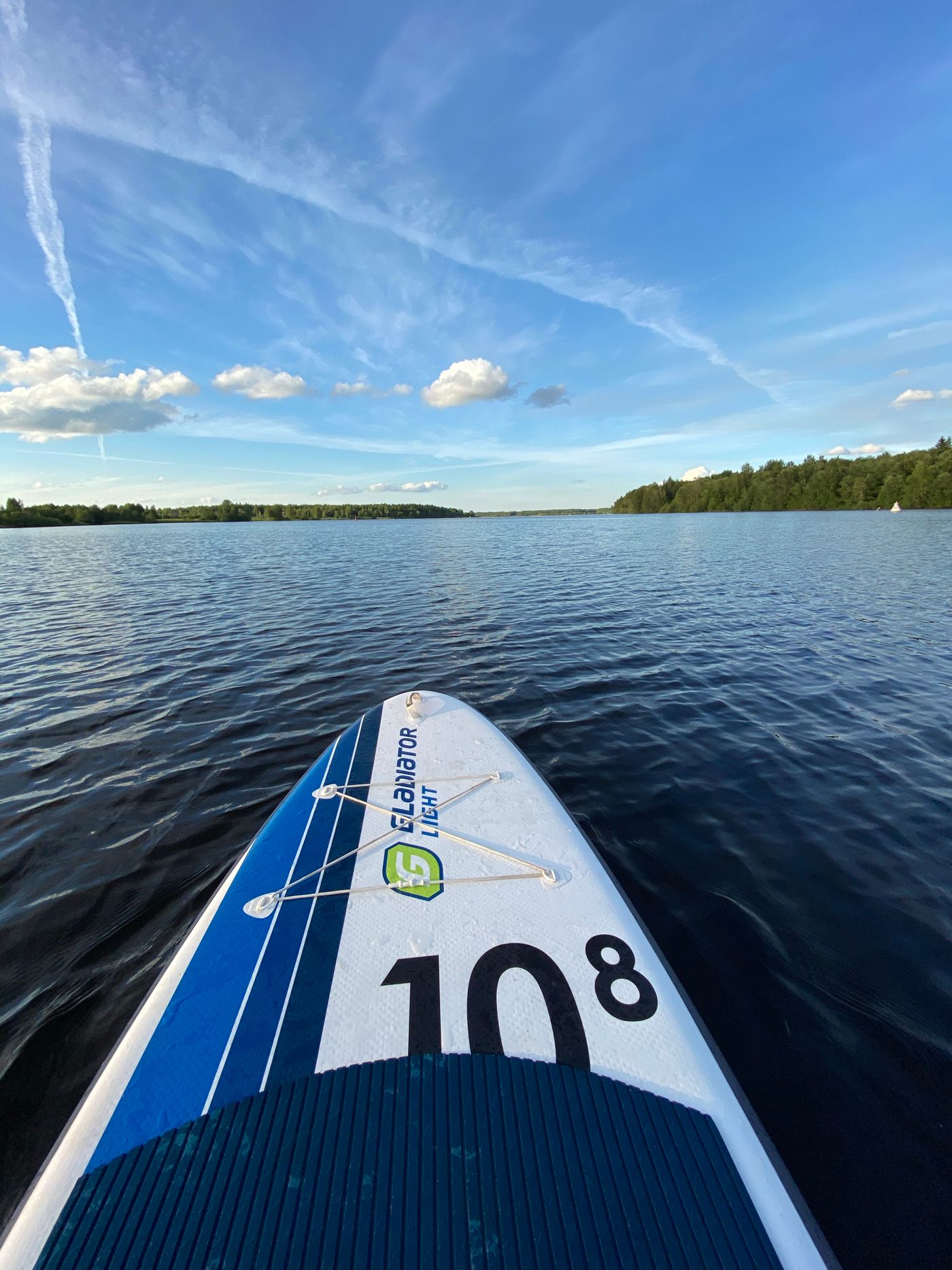 Close view of a stand-up paddleboard and paddle floating on calm water during a recreational outing