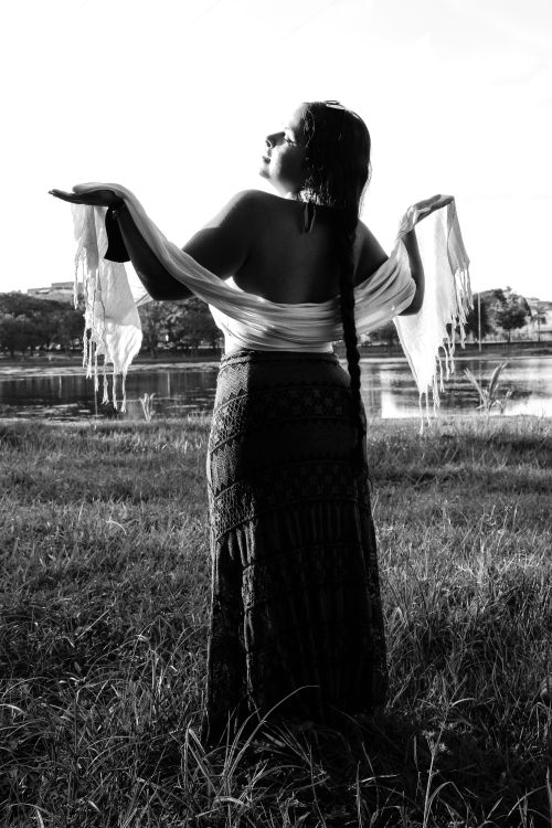 Free A woman stands gracefully by a lake, draped in a shawl, captured in monochrome. Stock Photo