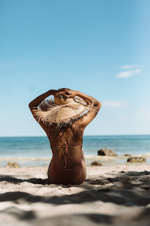 Backview of Woman in White Bikini sitting on Beach Shore in Tilt-Shift Lens 