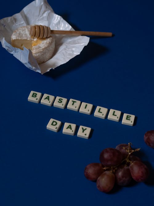 Scrabble Tiles Beside Grapes on Blue Surface
