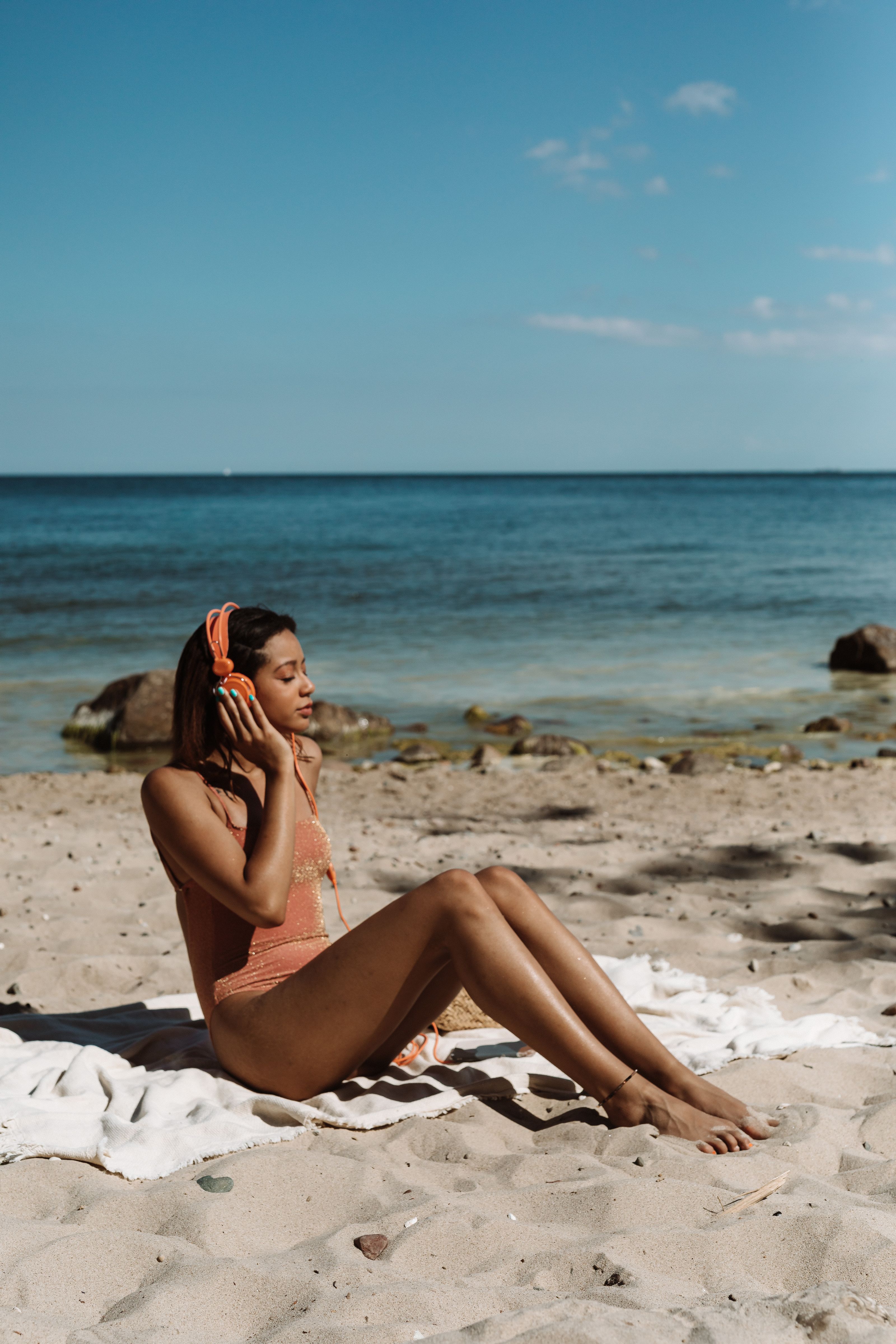 Uma mulher desfrutando de música enquanto toma sol na praia no verão.