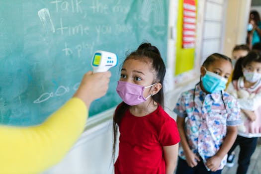 Children wearing masks have their temperature checked in a classroom setting.