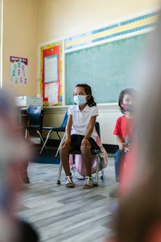 Children in a classroom setting wearing face masks, practicing safety during lessons.