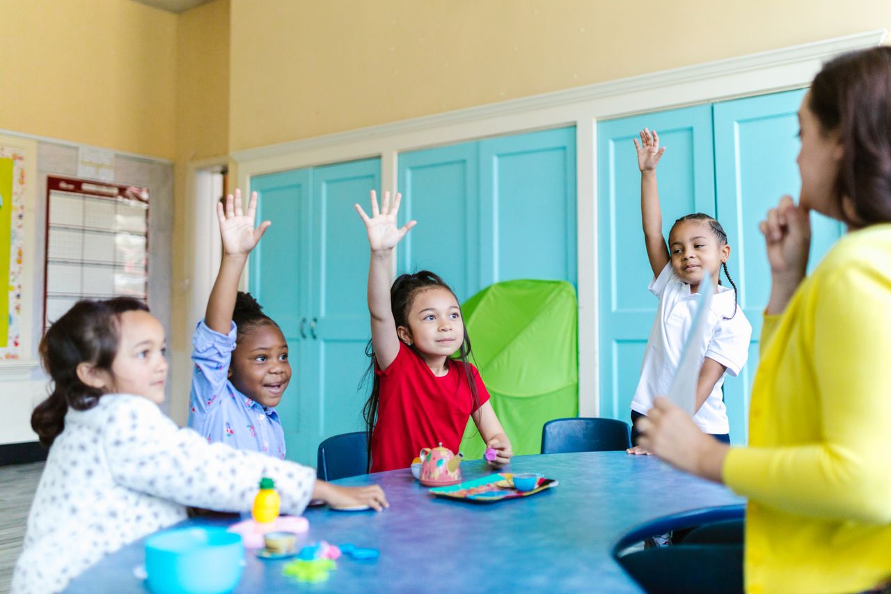 growth-mindset-wall-classroom Children raising hands eagerly in a colorful classroom