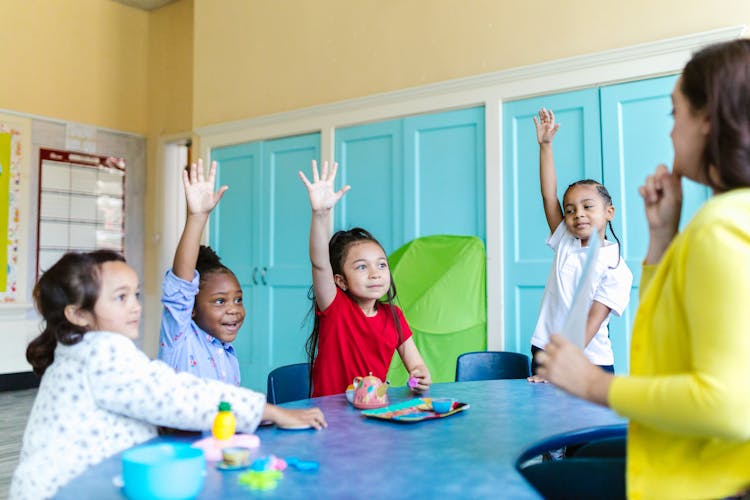 Group Of Kids Sitting On Chair In Front Of Table