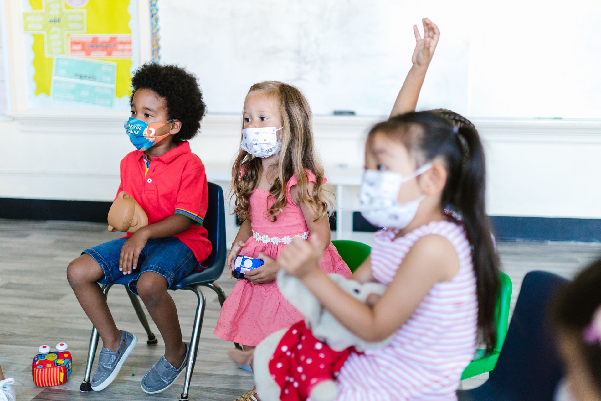 Children wearing face masks attentively participate in a preschool classroom.