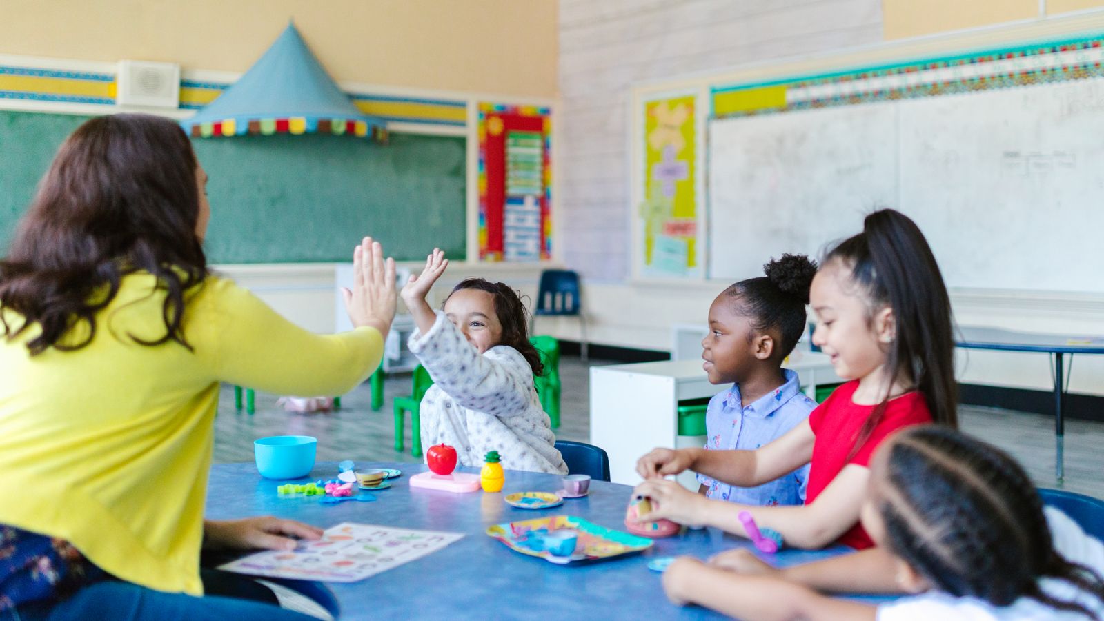 Teacher playing a hands-on game with young children while teaching English to young learners