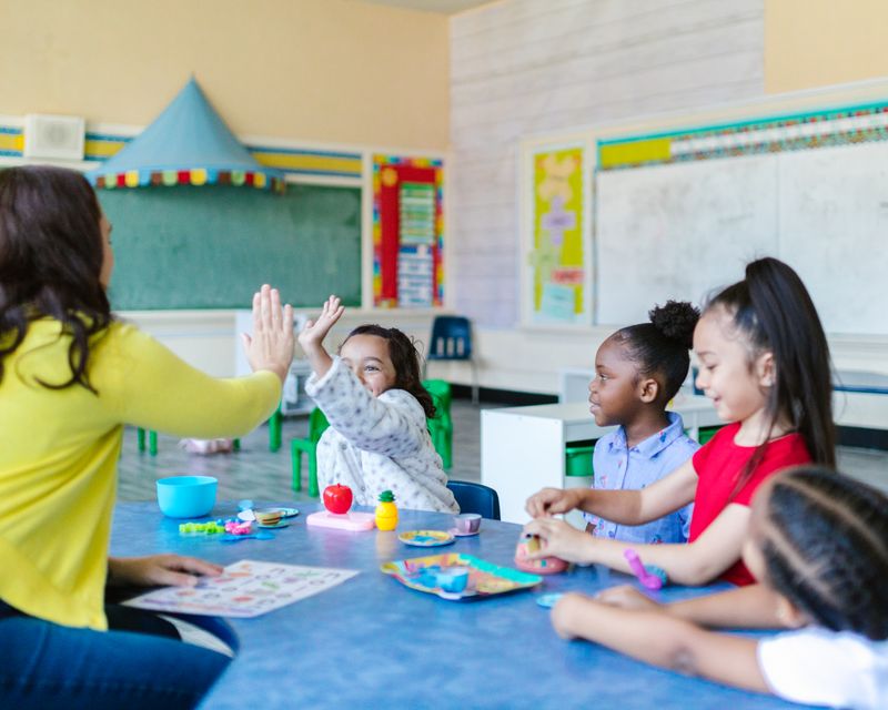 Children playing with their teacher in a childcare classroom