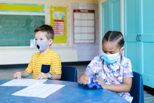 Two children wearing masks learn and play in a bright classroom setting, focusing on education and safety.