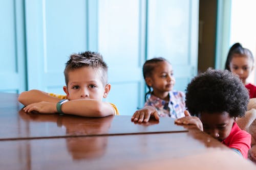 Free Boy in Yellow T-Shirt Leaning on Wooden Table Stock Photo
