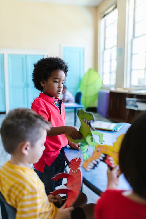 Free Kids Playing with Dinosaur Toys Inside a Classroom Stock Photo