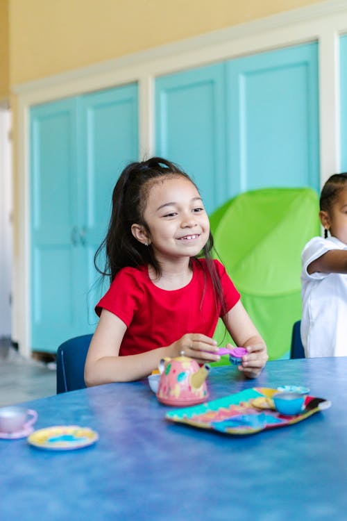 Girl in Red T-shirt Smiling and Holding a Plastic Toy